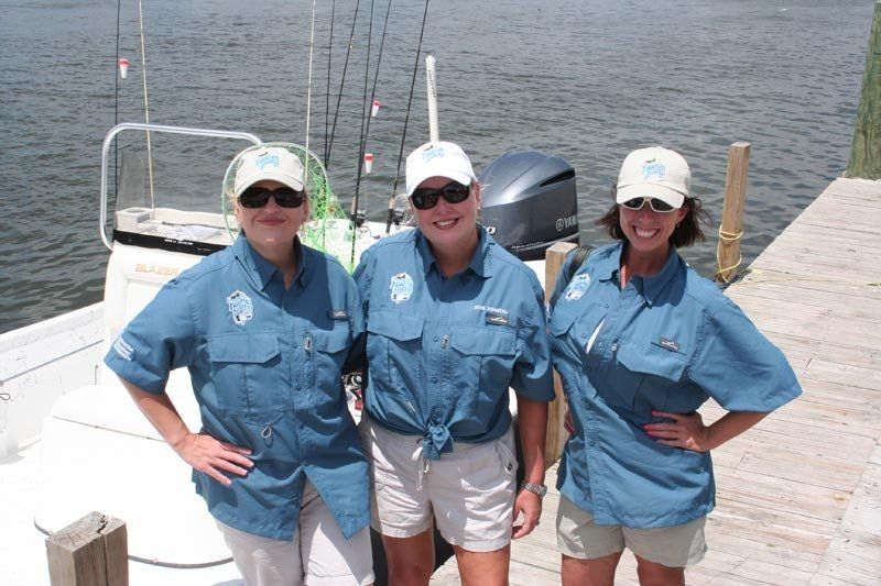 Three women are posing for a picture in front of a boat