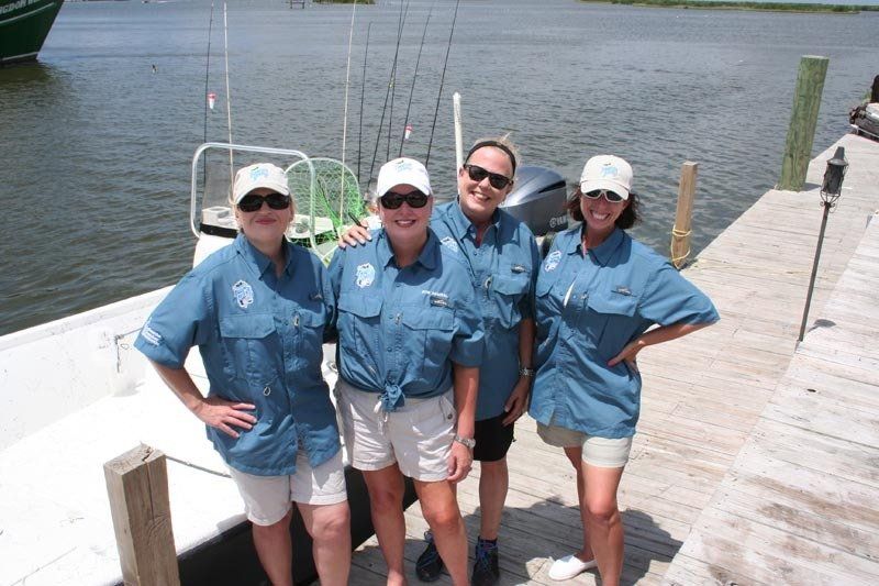 Four women are posing for a picture in front of a boat