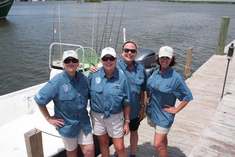 A group of women are posing for a picture in front of a boat