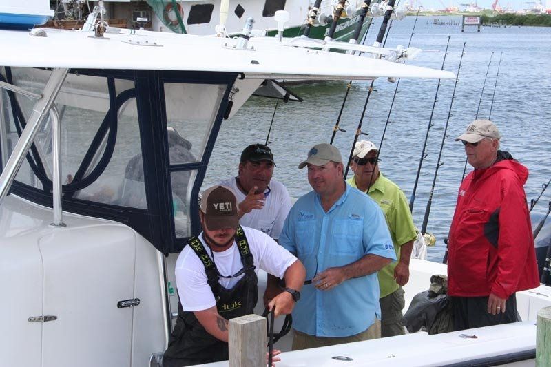 A group of men are standing on a boat with one wearing a hat that says yeti