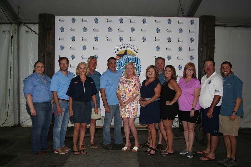 A group of people are posing for a picture in front of a wall that says ' purple ' on it