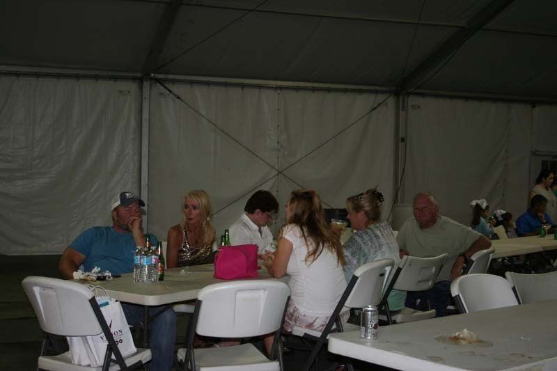 A group of people are sitting at tables in a tent.