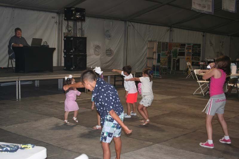 A group of children are dancing in front of a dj