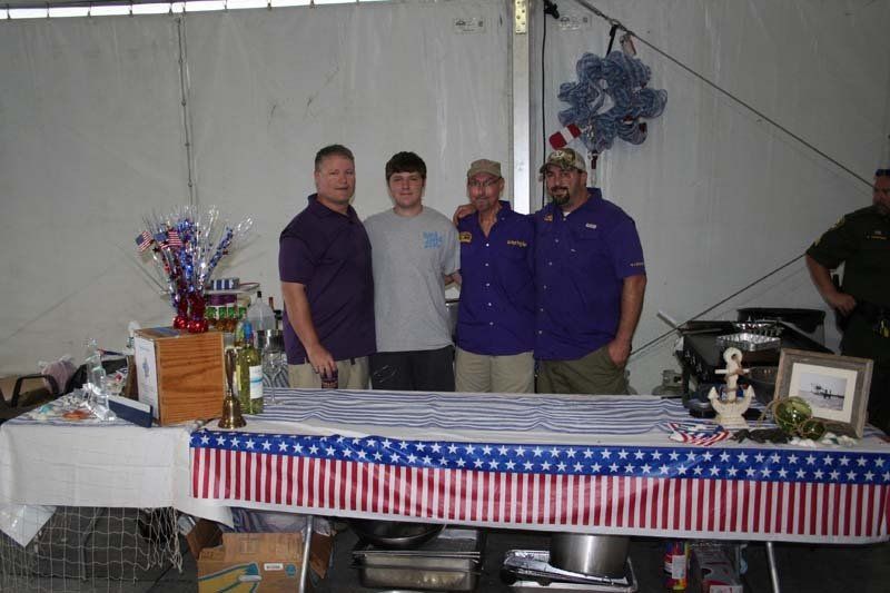 A group of men standing around a table with an american flag table cloth
