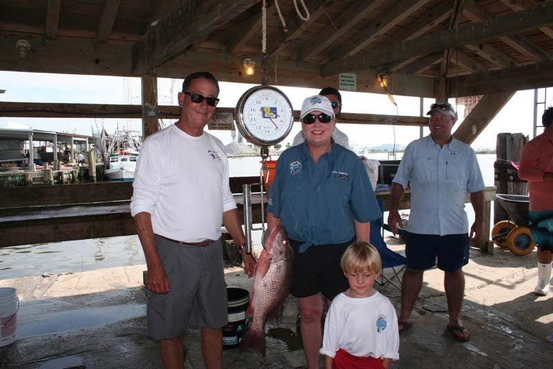 A man is holding a large fish next to a boy