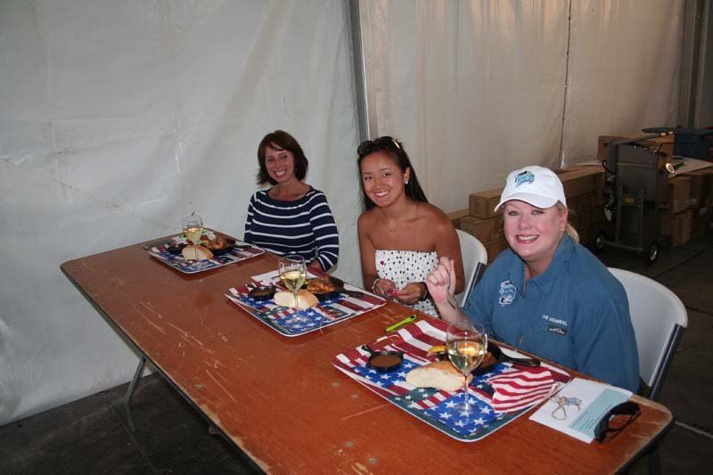 Three people are sitting at a table with plates of food on it