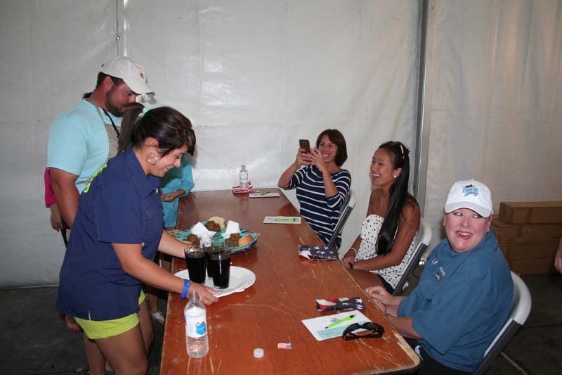 A woman is serving food to a group of people sitting at a table.