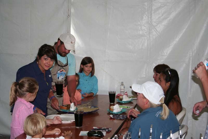 A group of people are sitting around a table with plates of food.