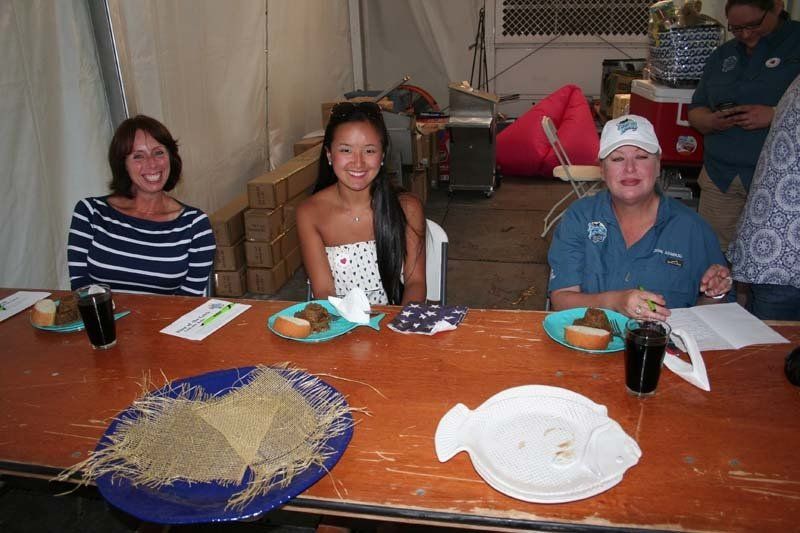 Three people are sitting at a table with plates of food and drinks