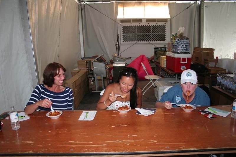 Three people are sitting at a table eating food