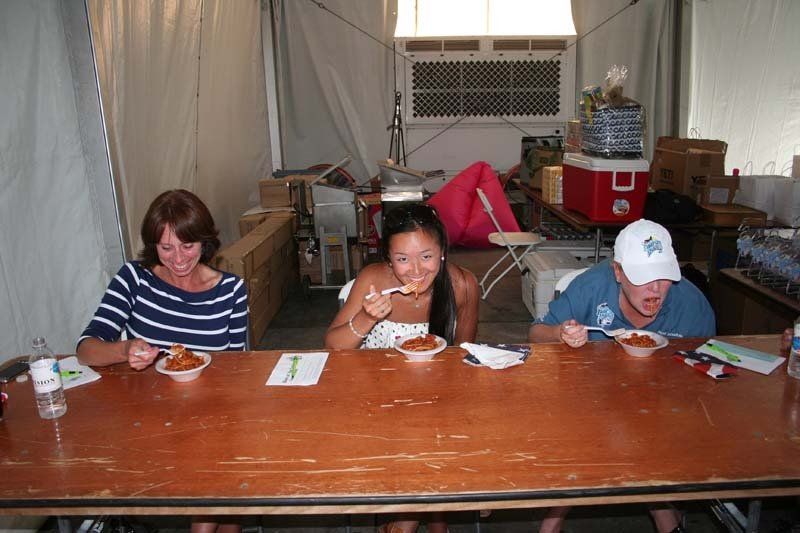 Three people are sitting at a table eating food