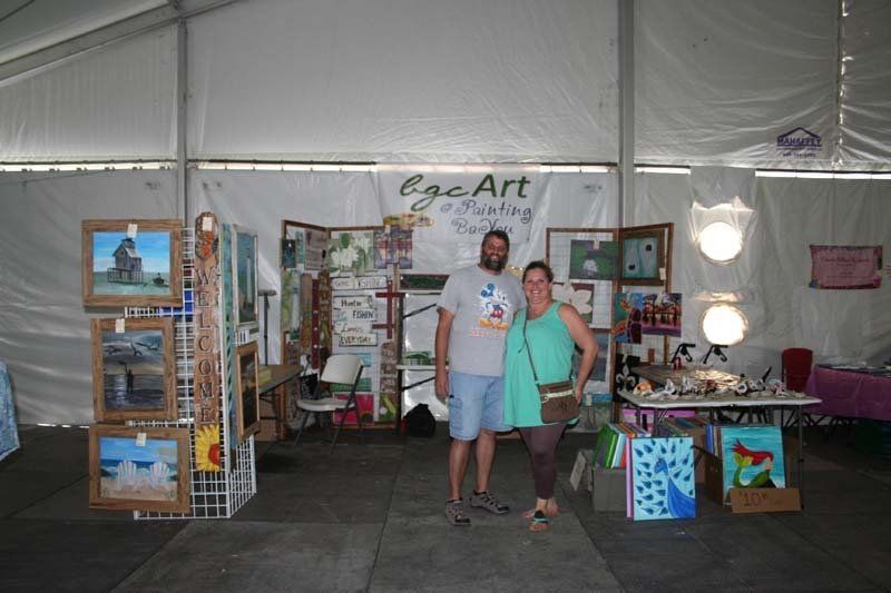 A man and a woman are standing in front of a sign that says ege art