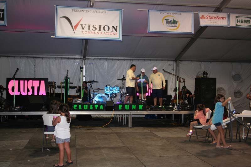 A girl stands in front of a stage with a sign that says clusta funk