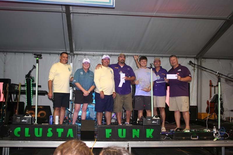 A group of men are standing on a stage in front of a sign that says clusta funk