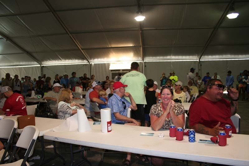 A group of people are sitting at tables in a tent.