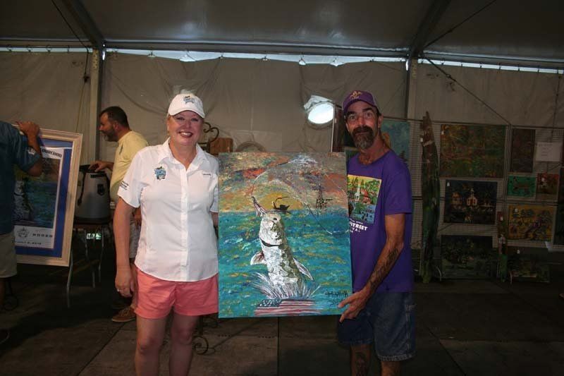 A man and a woman are holding a painting of a fish in the water.