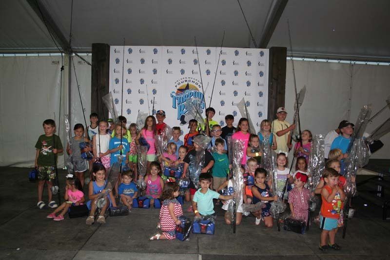 A group of children posing for a picture with fishing rods