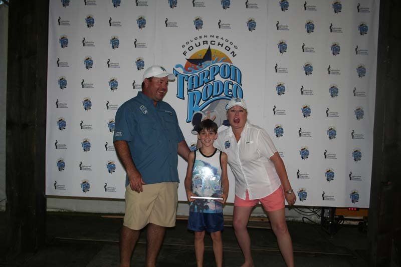 A man and woman standing next to a boy in front of a sign that says triumph rodeo