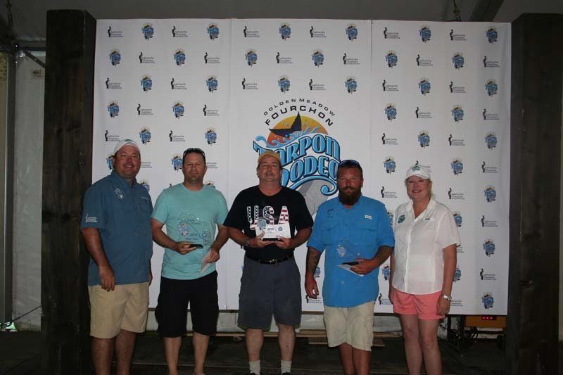 A group of people are posing for a picture in front of a wall that says ' champions ' on it.