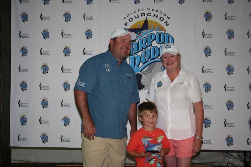 A man , woman and child are posing for a picture in front of a wall that says fourchan