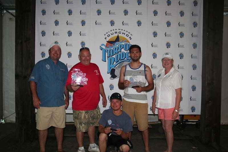 A group of people standing in front of a wall that says tarpon boats