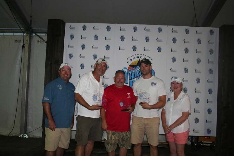 A group of people posing for a picture in front of a wall that says ' fishing ' on it