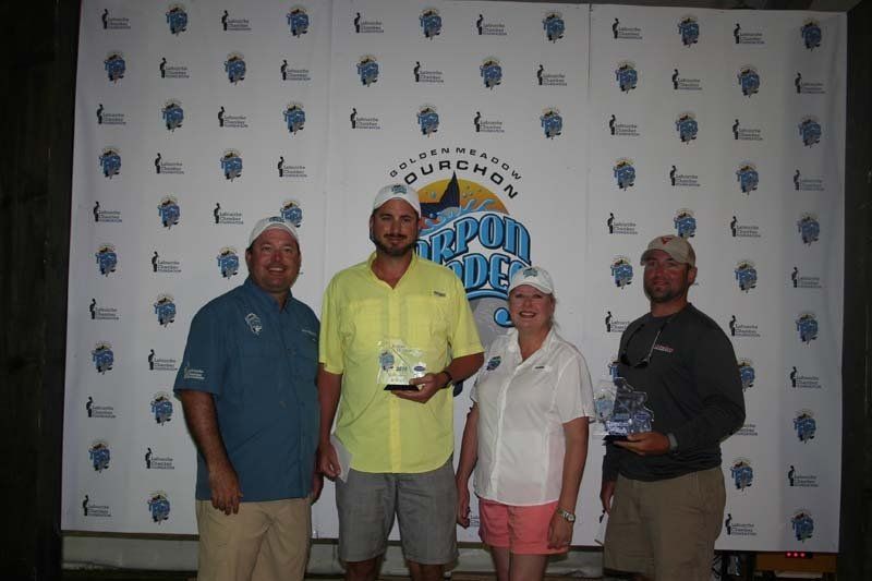 A group of people are posing for a picture in front of a wall that says aquachos