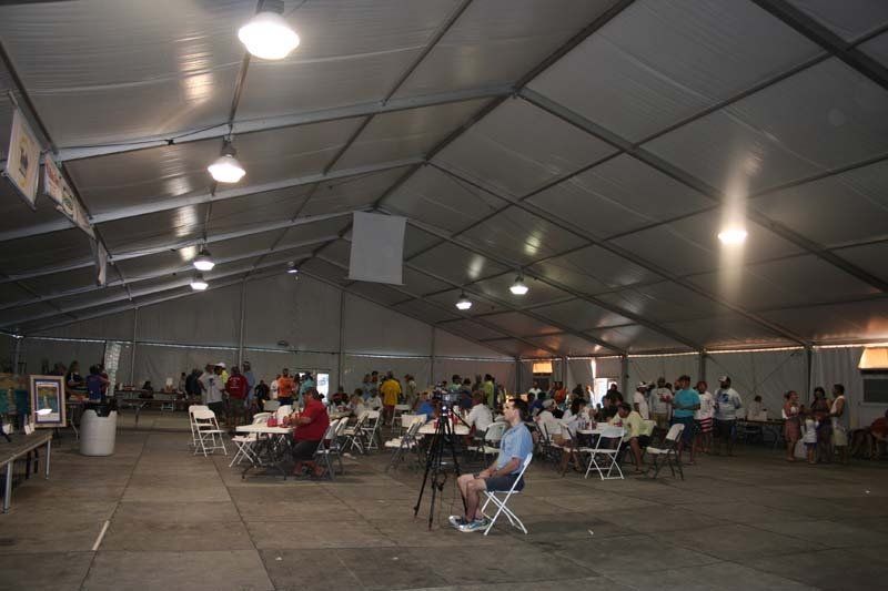 A group of people are sitting at tables under a tent