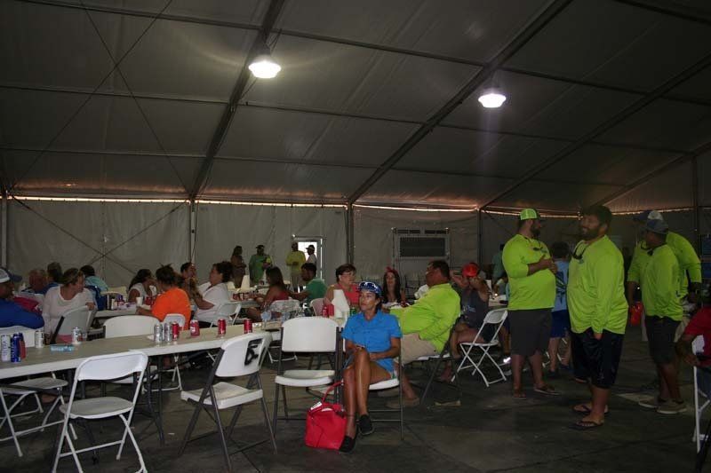 A group of people are sitting at tables under a tent.