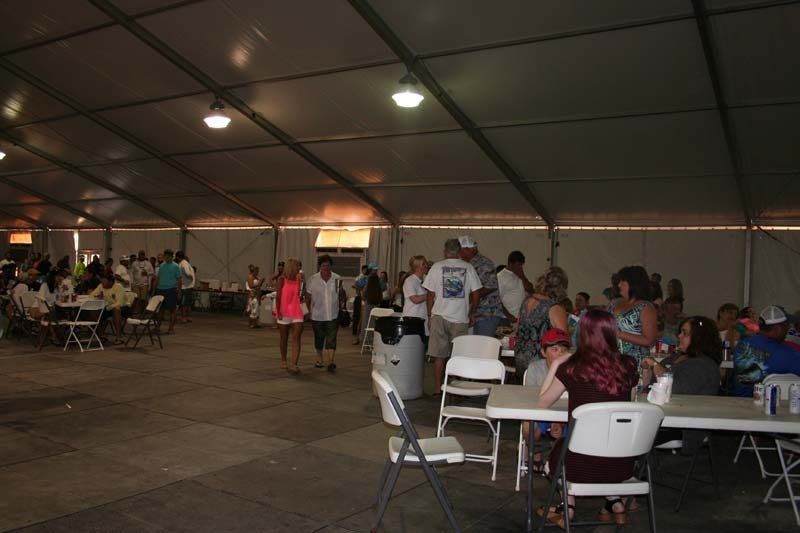 A group of people are sitting at tables under a tent.
