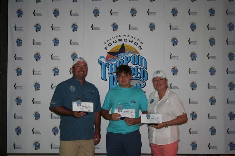 Three people are posing for a picture in front of a wall that says fourchan.