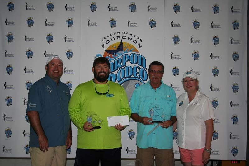A group of people are posing for a picture in front of a wall that says fourchon