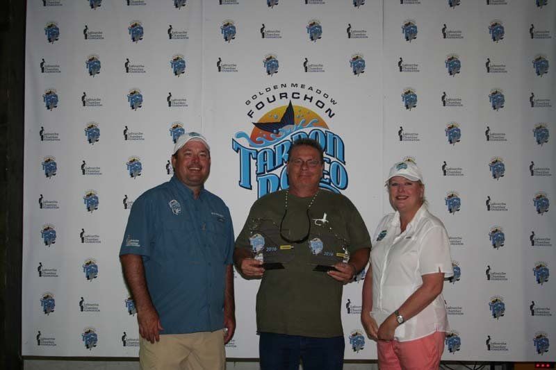Three people are posing for a picture in front of a wall that says bourbon on it