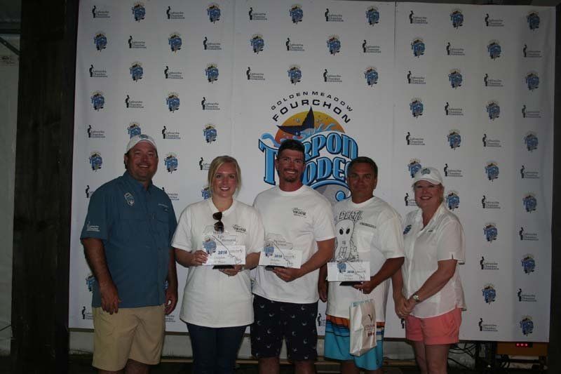A group of people are posing for a picture in front of a wall that says fourth tide.