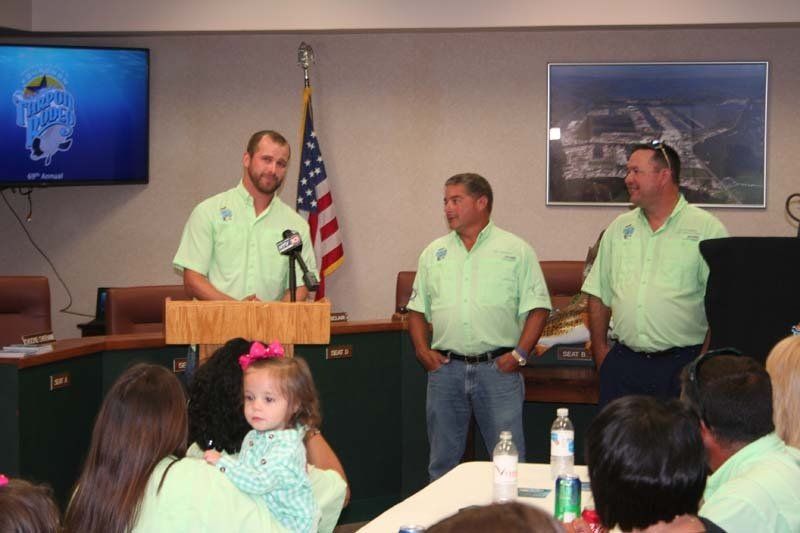 Three men in green shirts stand in front of a podium