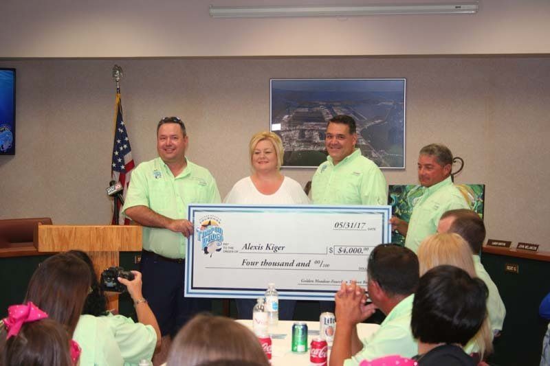 A group of people in green shirts are holding a large check
