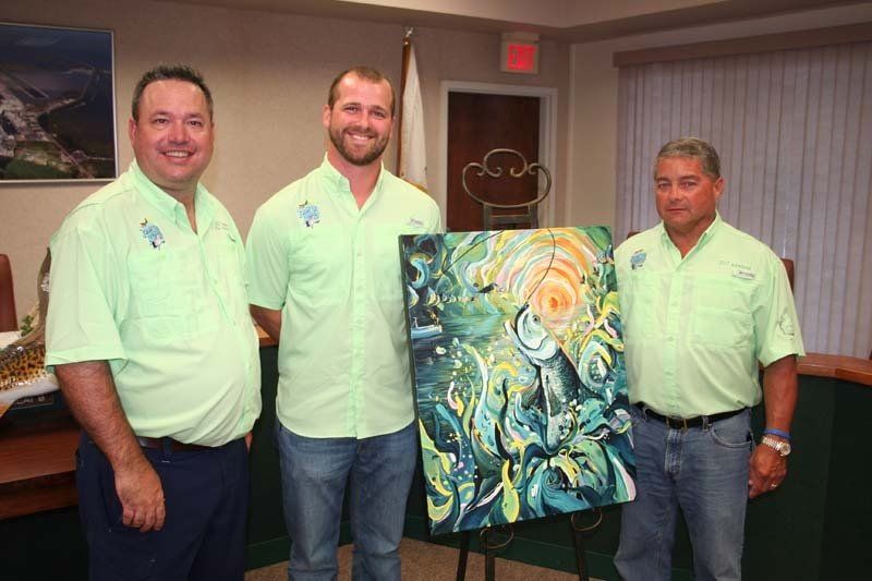 Three men are standing next to each other holding a painting.