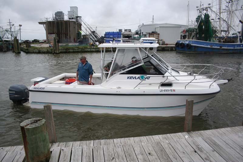 A man stands on a dock next to a boat that says voyager