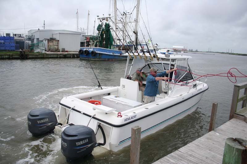 A man in a blue shirt is steering a boat in the water