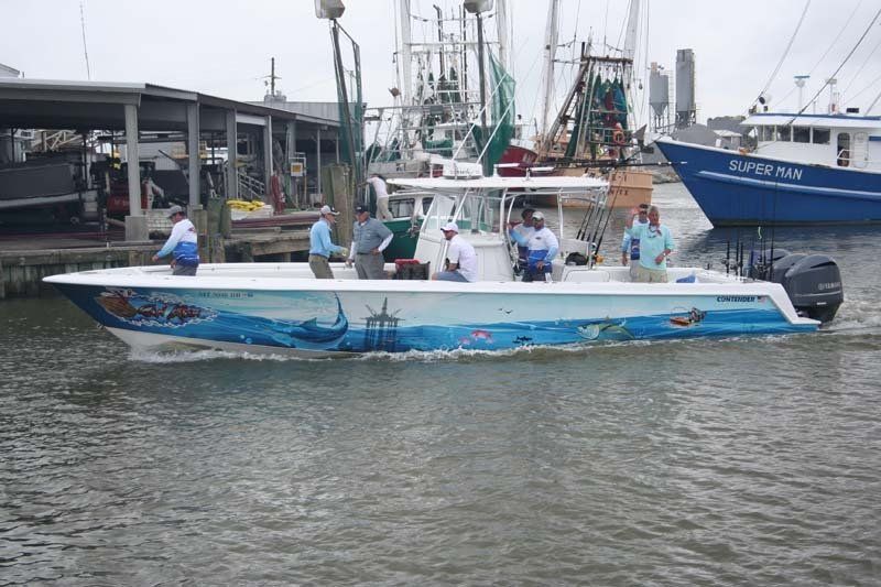 A boat with a painting of a shark on the side is floating on a body of water.