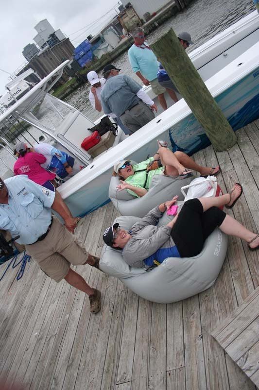 A group of people are sitting on a dock near a boat