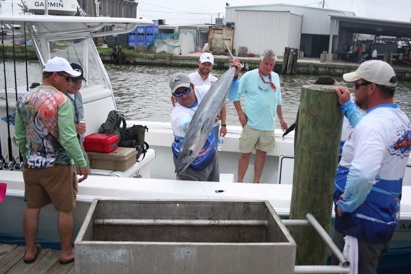 A group of men are standing on a boat holding a large fish.