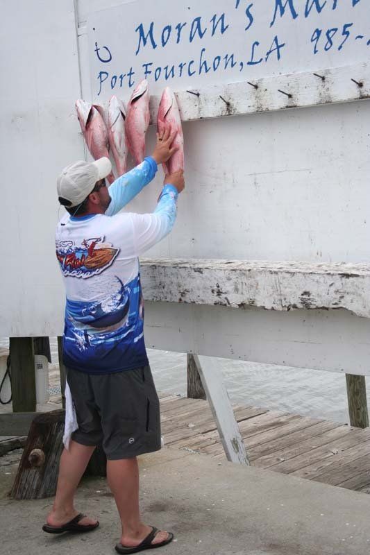 A man is standing in front of a sign that says moran 's marina