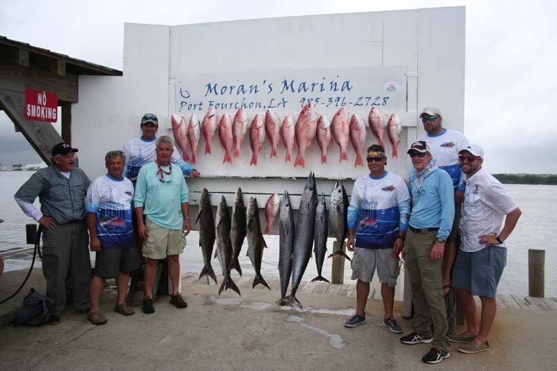 A group of men standing in front of a sign that says moran 's marina