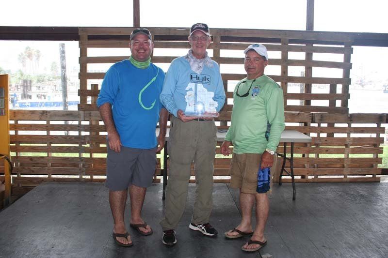 Three men standing next to each other in front of a wooden wall