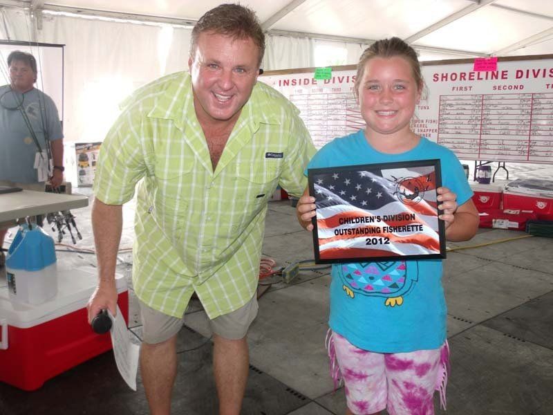 A man and a girl are posing for a picture and the girl is holding a framed picture of an american flag