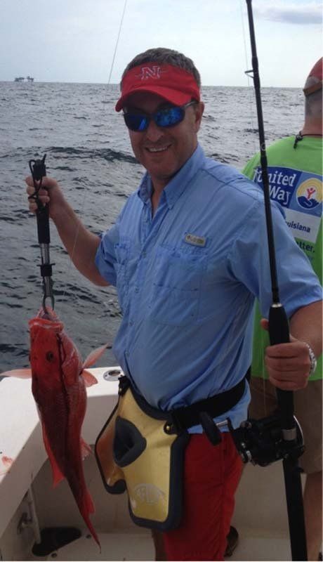 A man on a boat holding a red fish