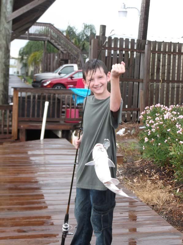 A young boy is holding a fishing rod and a fish