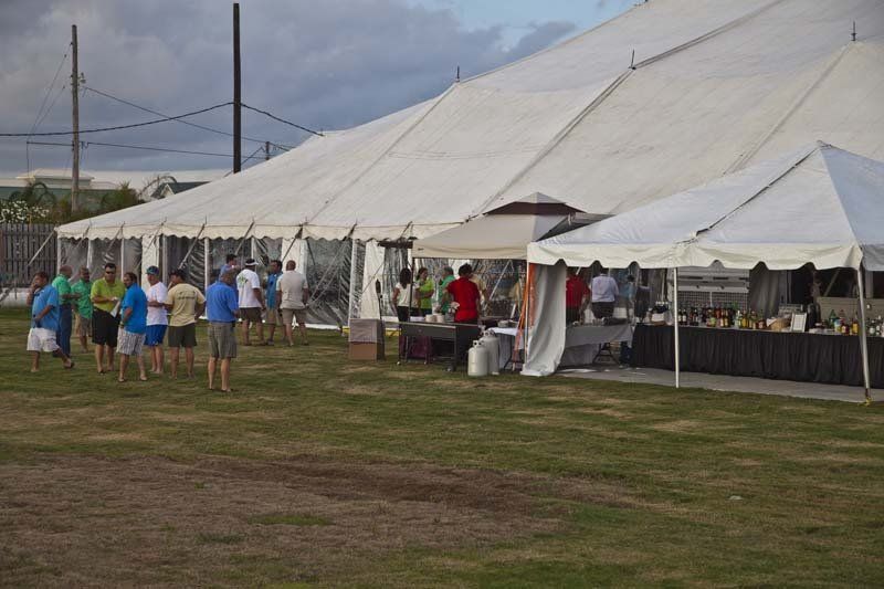 A group of people are standing in front of tents in a field.