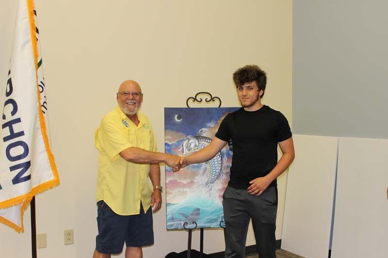 Two men are shaking hands in front of a painting.
